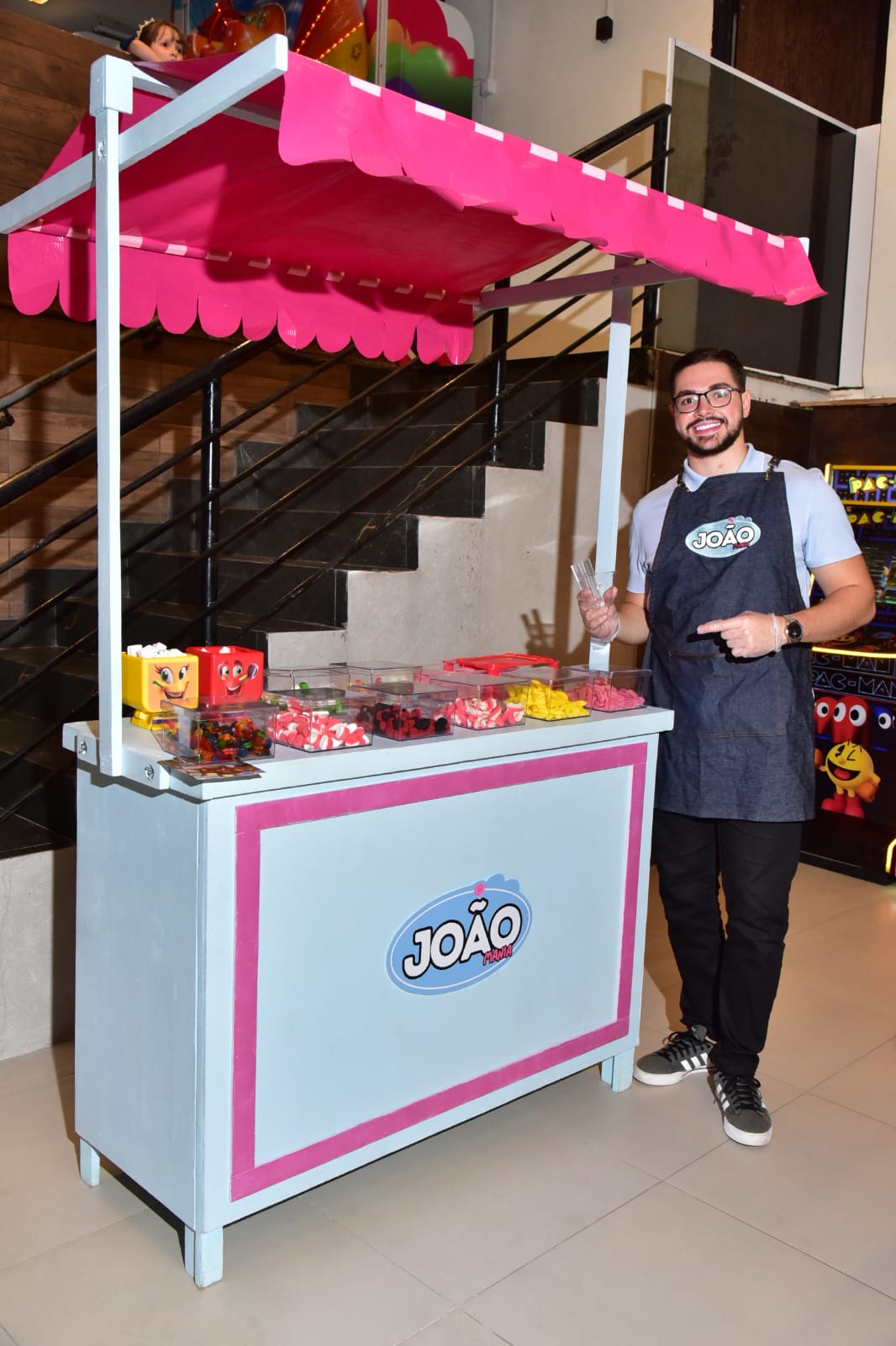 João, fundador da João Mania, ao lado da estação de doces